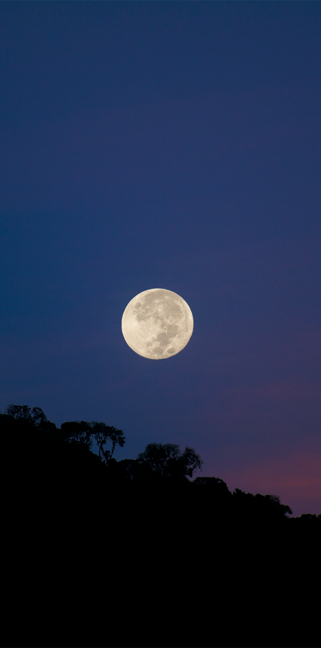 Moon over a dark landscape at dusk